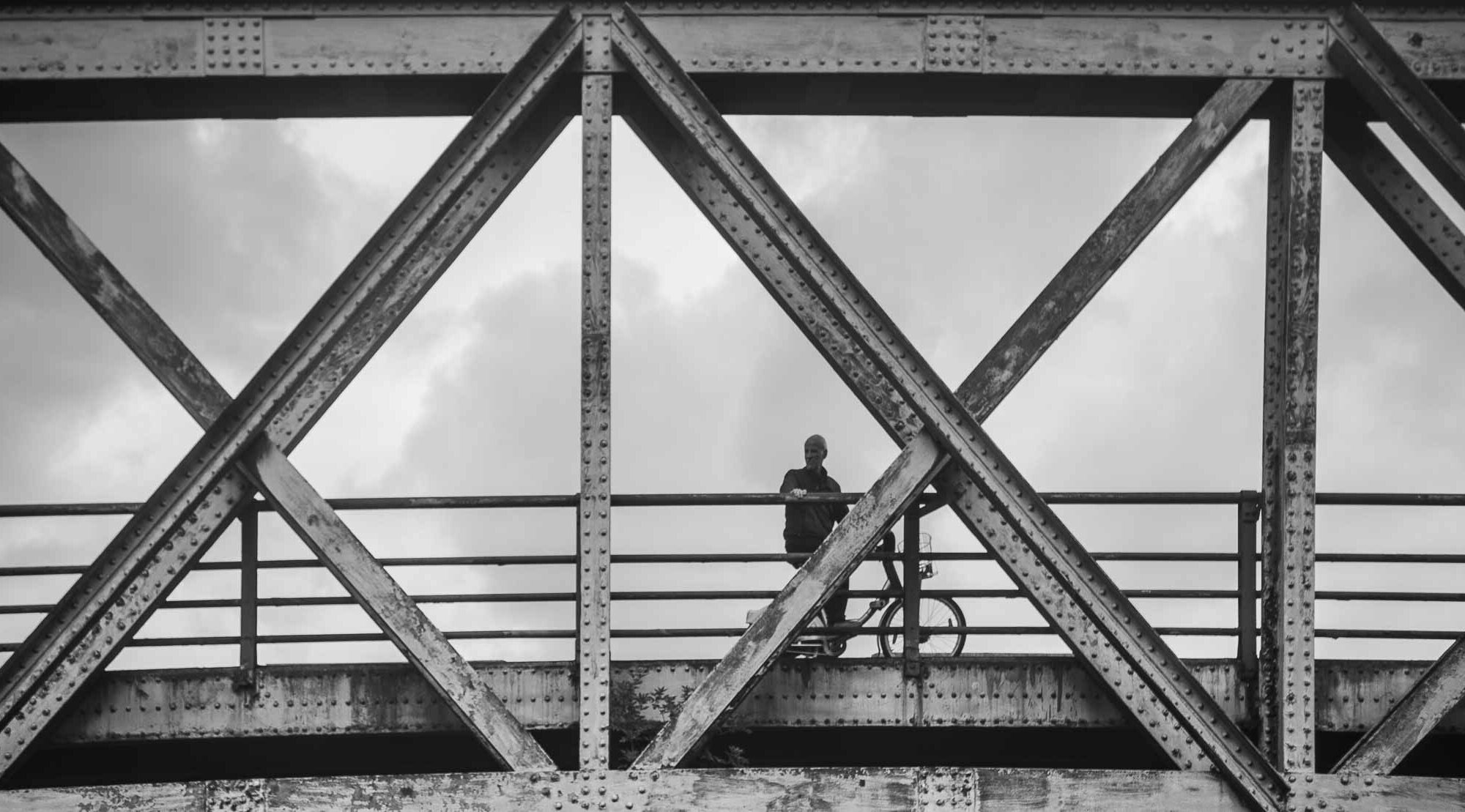 silhouette de cycliste appuyé sur un pont en métal