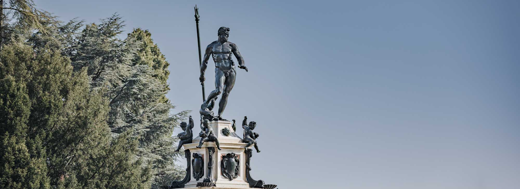 Détail de la fontaine de Neptune où le Dieu tient son trident devant un ciel bleu