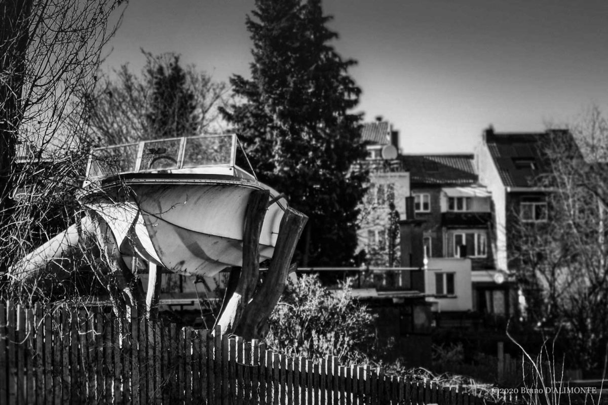 Photographie de Bruno D'Alimonte illustrant de façon humoristique une conséquence du réchauffement climatique : la montée du niveau de la mer avec pour conséquence éventuelle, la navigation en ville. L'image montre un petit bateau moteur posé sur un arbre et qui attend la montée des eaux à Bruxelles.