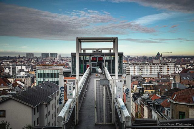 Vue panoramique de Bruxelles avec l'ascenseur des Marolles et un passant accompagné de son chien. 