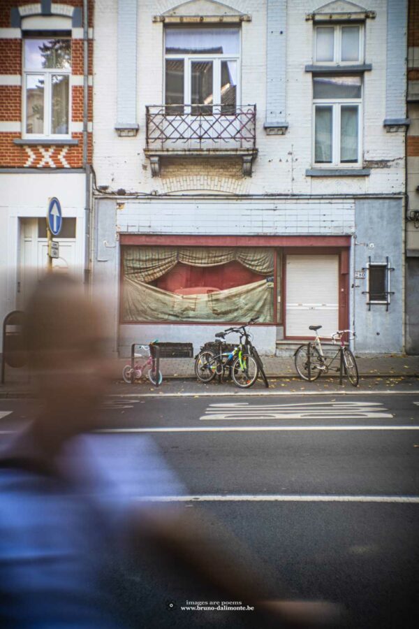 Silhouette floue de cycliste passant devant la scène d'une façade paisible où sont parqués des vélos